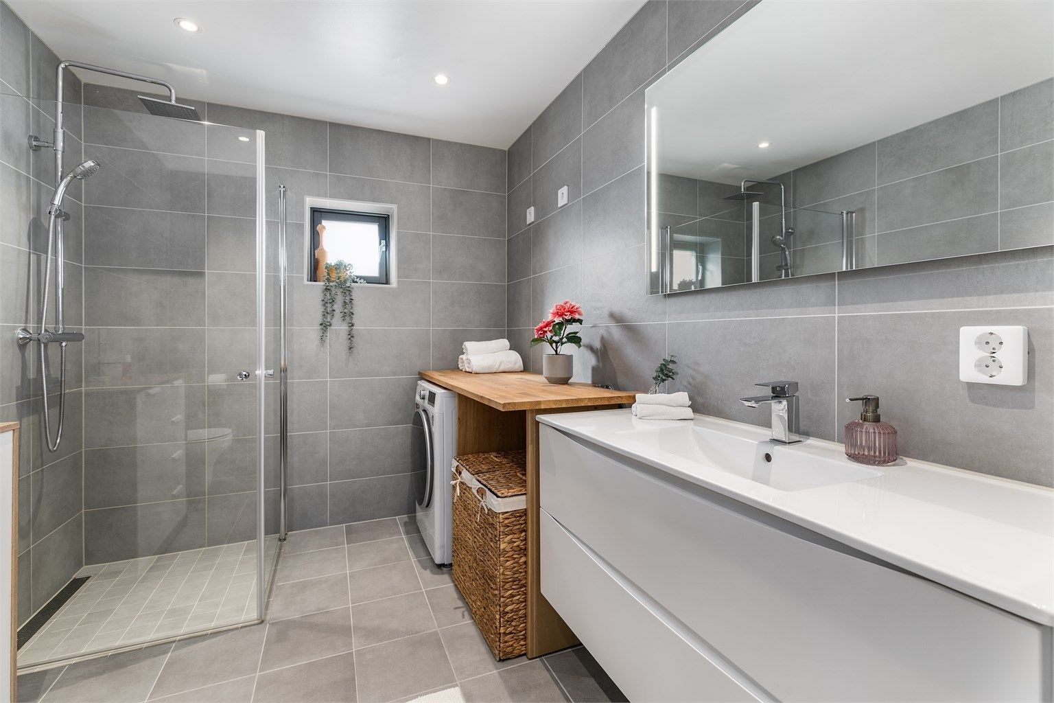 Badet er smart innredet til kombinert formål som vaskerom. Dusjdørene kan svinges inn for enklere tilgang til vaskemaskinen.