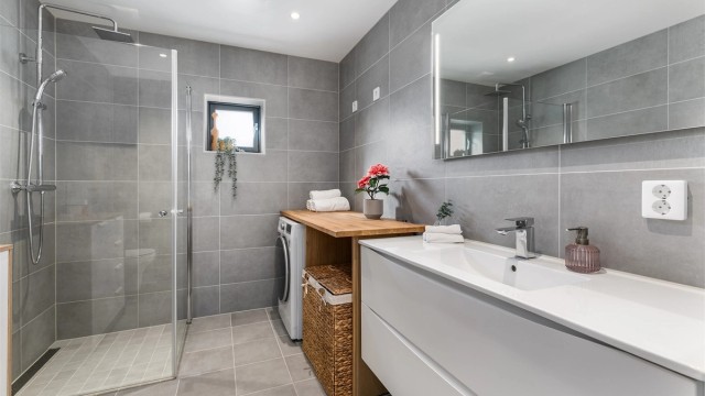 Badet er smart innredet til kombinert formål som vaskerom. Dusjdørene kan svinges inn for enklere tilgang til vaskemaskinen.
