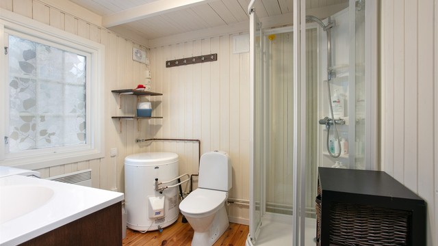 Badet er innredet med dusjkabinett, toalett og panelovn.
