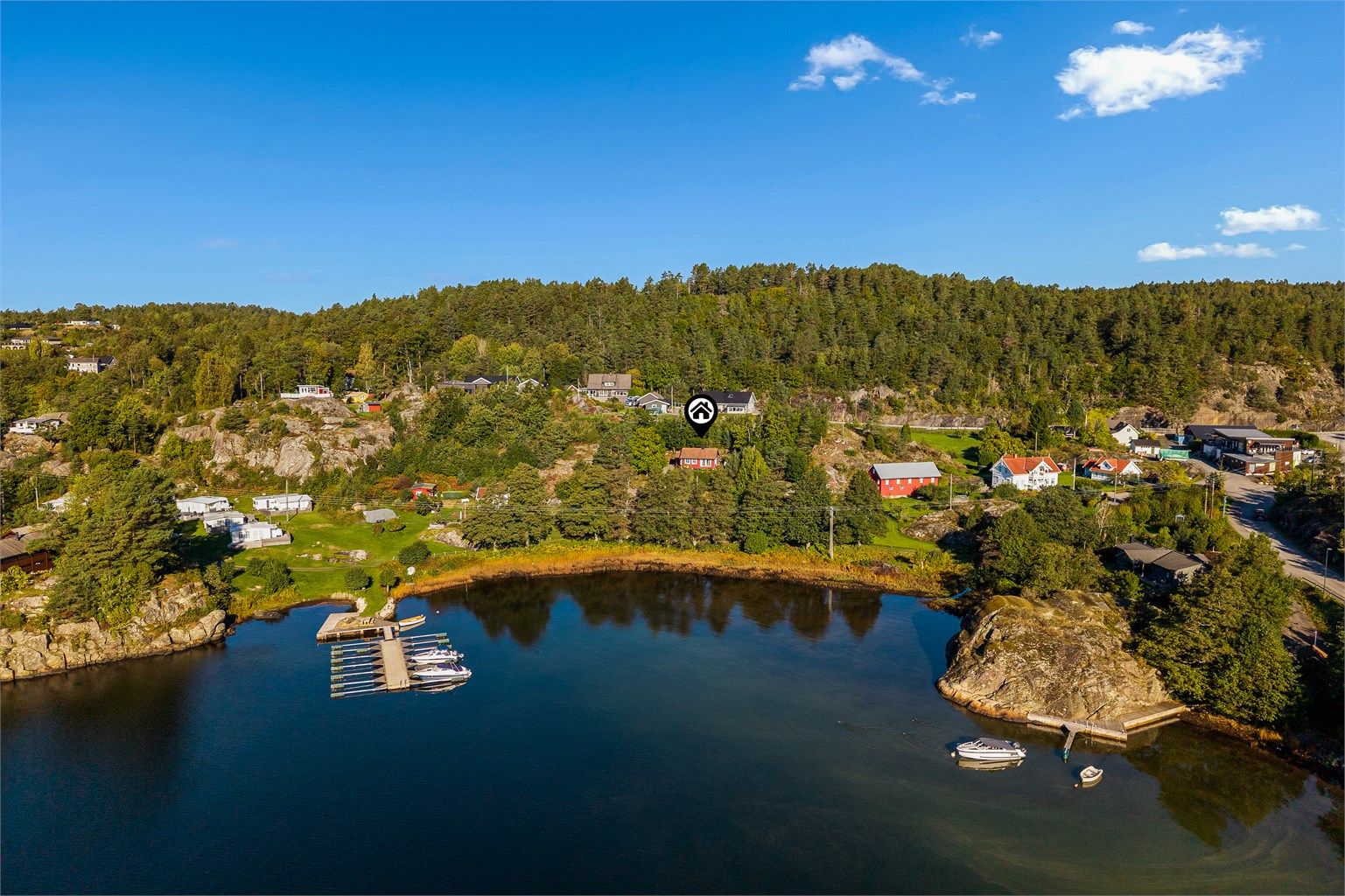 Kyststien går langs sjøen rett nedenfor og dagligvarebutikken i området ligger bare noen få minutters gange fra hytta. Den sees til høyre i bildet.