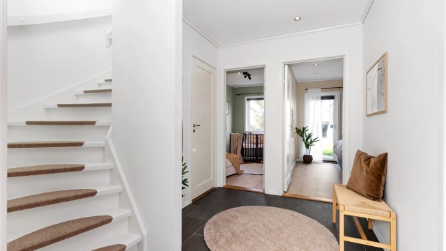 Trapperom med hvitmalt tretrapp som leder opp til oppholdsrommene i andre etasje.