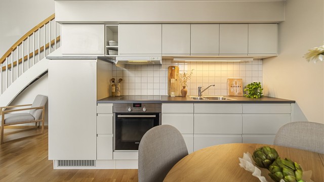 Det er montert en moderne kjøkkeninnredning med slette fronter og laminatbenkeplate. Fliser mellom benkeplate og overskap. Integrert oppvaskmaskin, platetopp, stekeovn og kjøleskap i høyskap medfølger.