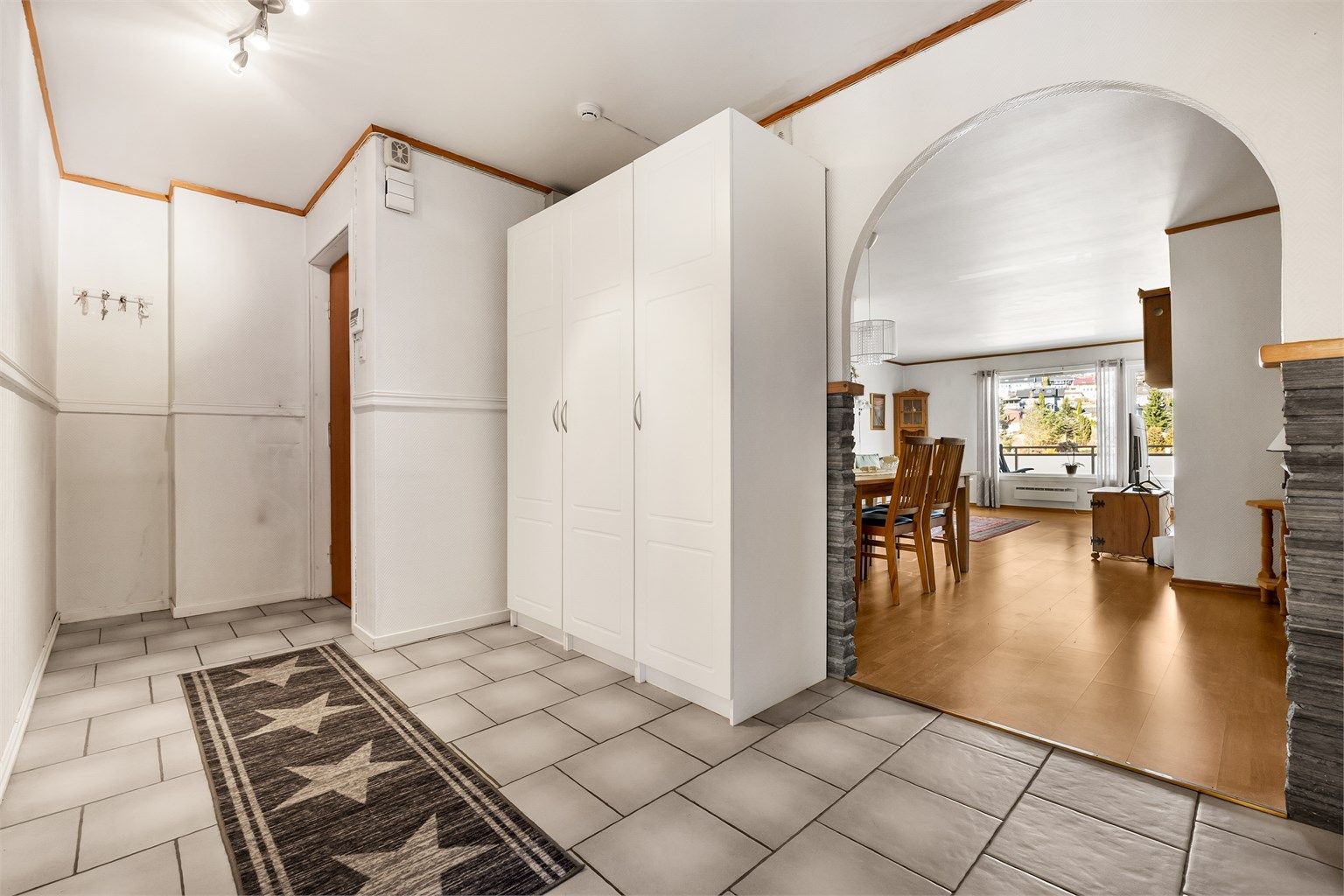 Entréen har flislagt gulv og en plassbygd garderobeløsning som gir rikelig med oppbevaring for yttertøy og sko.
