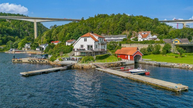 Lang strandlinje, egen brygge, båthus, garasje, terrasser, uteplasser og en stor gresslette er noe av det vi finner i Langangsveien 233.