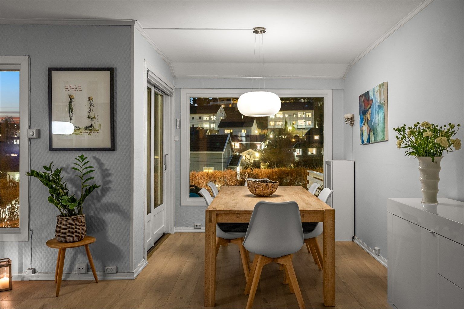 Spisestuen med utsikt mot nabolaget på kveldstid.