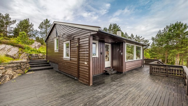 Den store terrassen i trekonstruksjoner omkranser deler av hytta.