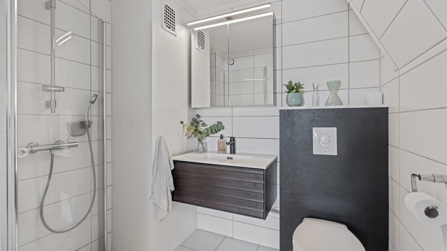 Badet har flislagte overflater, gulvvarme og vegghengt toalett.