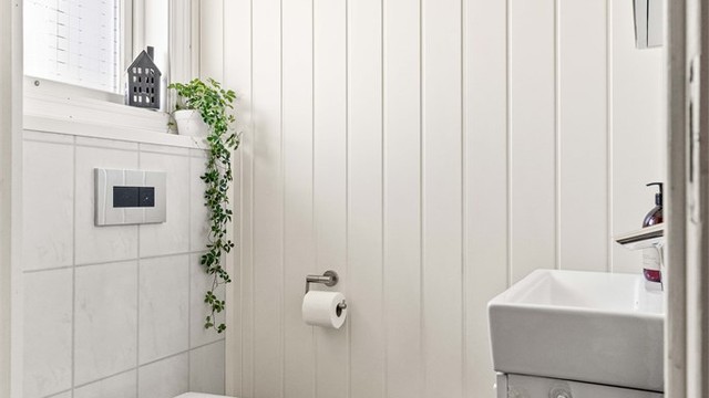 Praktisk toalettrom i første etasje med vegghengt toalett og parkett på gulvet.