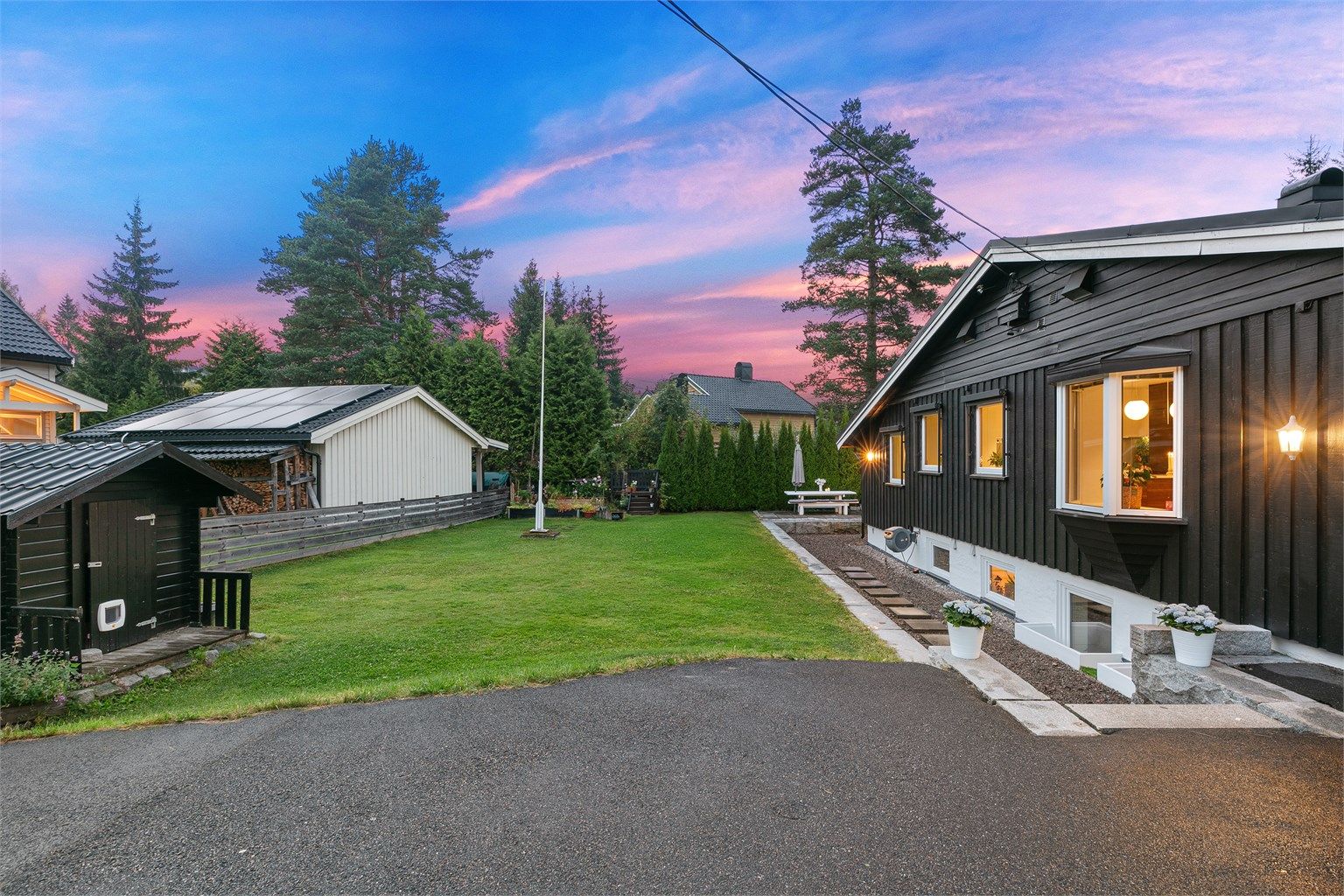 Pent opparbeidet hage med hekk, plen og beplantning.