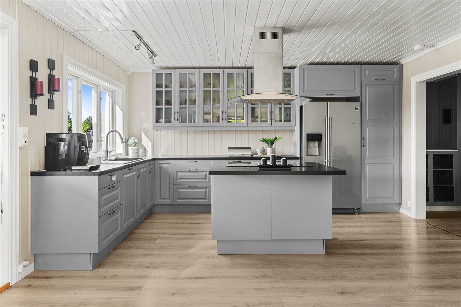 Kjøkkenet med profilerte fronter og benkeplate med laminert overflate. Integrert oppvaskmaskin, stekeovn og nedfelt platetopp på kjøkkenøy.