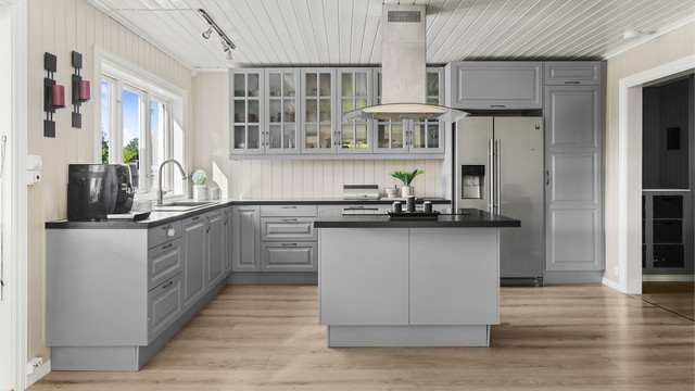 Kjøkkenet med profilerte fronter og benkeplate med laminert overflate. Integrert oppvaskmaskin, stekeovn og nedfelt platetopp på kjøkkenøy.
