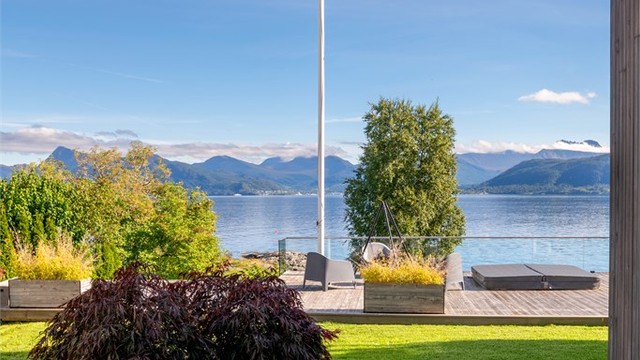 Opparbeidet plenareal og beplantning omkranser terrassen mot sjøsiden.