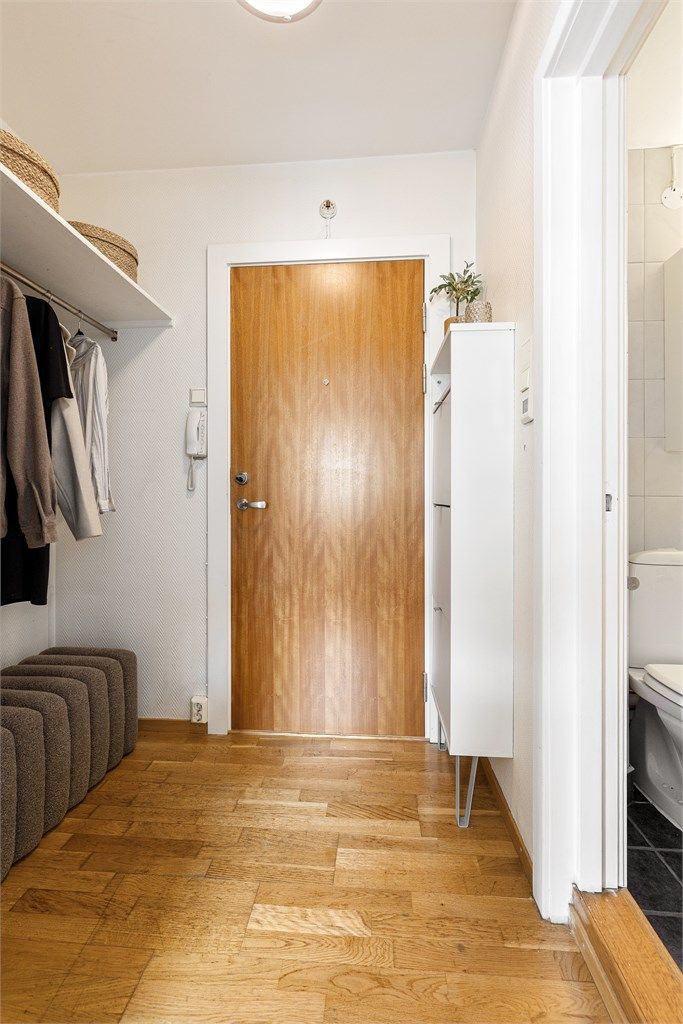 Entré med parkett på gulv og malte vegger. Her er det et plassbygget skap samt nisje med plass til oppheng av yttertøy og sko.
