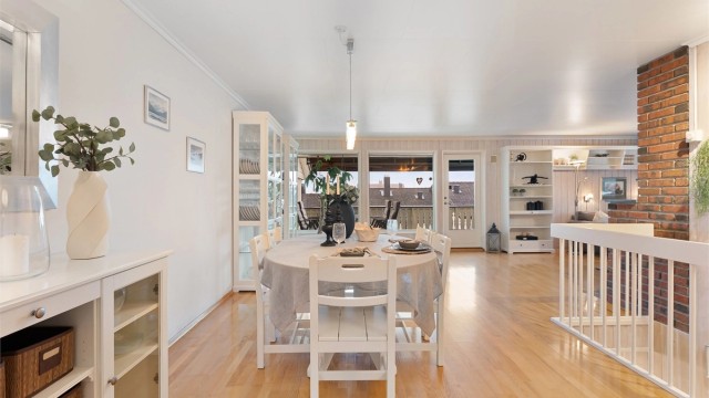 Den romslige stuen og spisestuen har gjennomgående parkettgulv og utgang til en stor veranda.