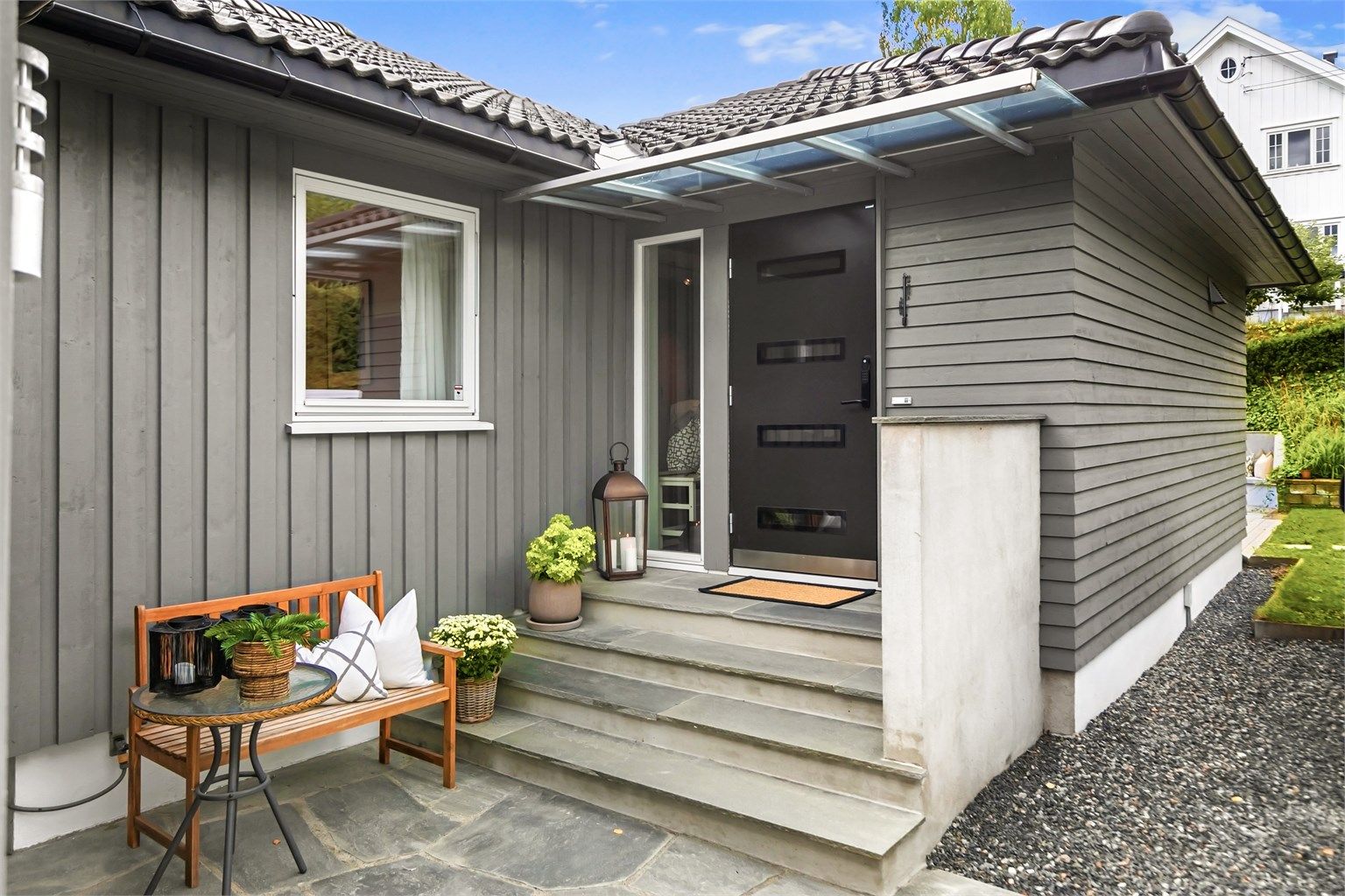 Inngangsparti med glassoverbygg, skifertrinn og markterrasse.