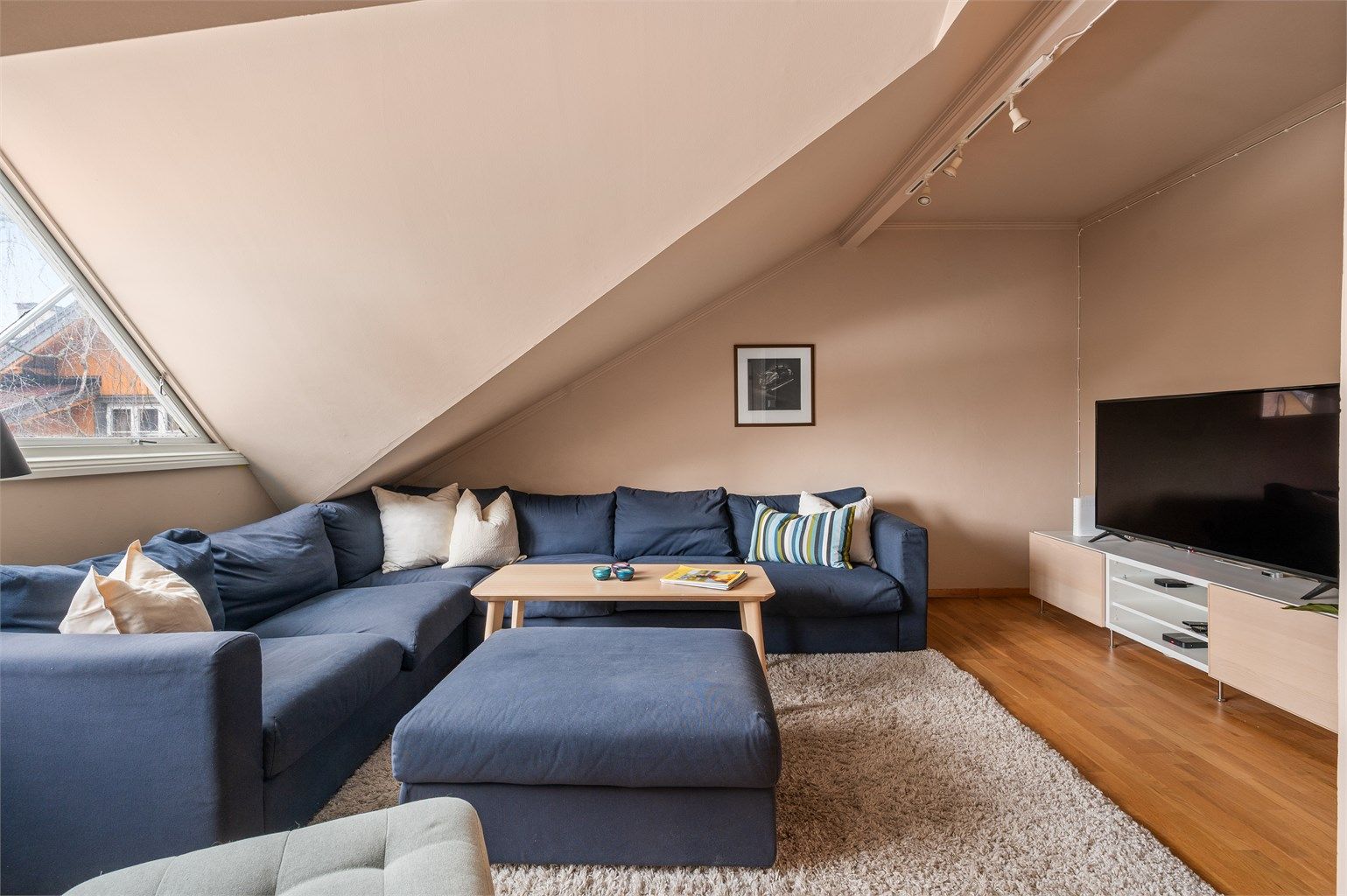Rommet har god plass til sofamøblement og byr på et hyggelig utsyn mot bakgården. 