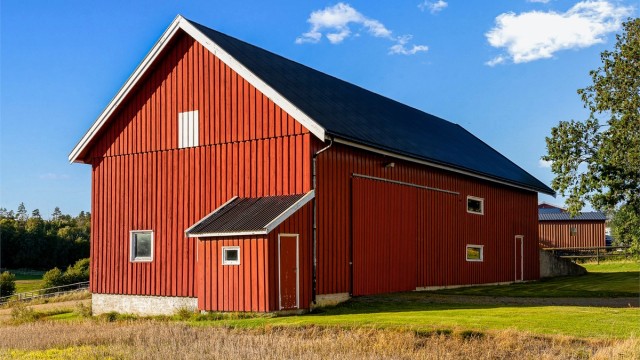 Romslig låve med stående kledning og rikelig oppbevaringsplass for redskap og utstyr.