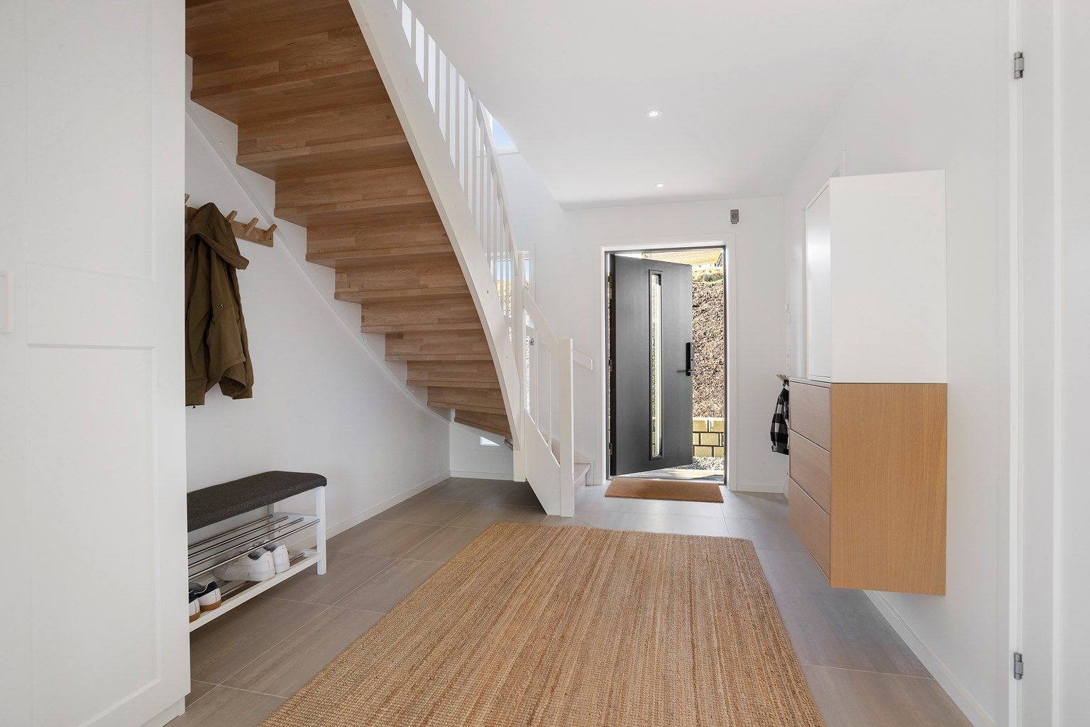 Man kommer inn i en romslig flislagt entré med flislagt gulv og varmekabler