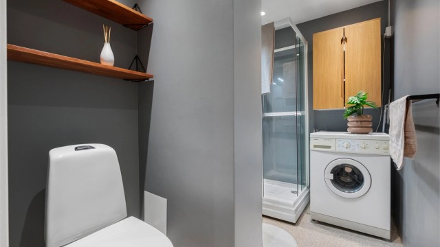 Videre er badet innredet med servantskap med speil og lys, dusjkabinett og toalett.