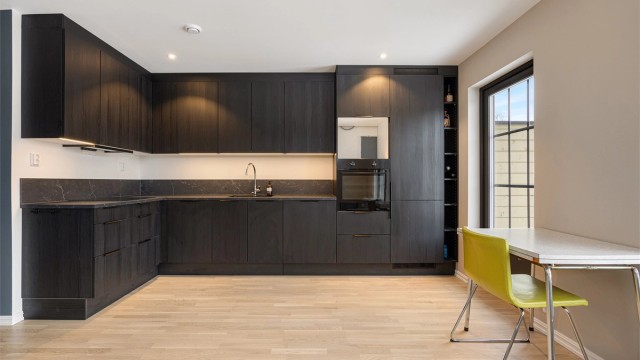 Stilrent og moderne kjøkken i L-form med sorte, glatte fronter og god skapplass.