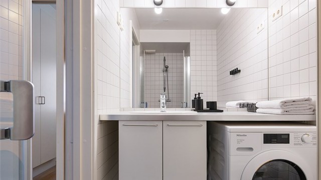 Badet er innredet med vegghengt servantinnredning med nedfelt vask i benkeplate, speil med lys og stikkontakt over servant og veggfestet toalett.