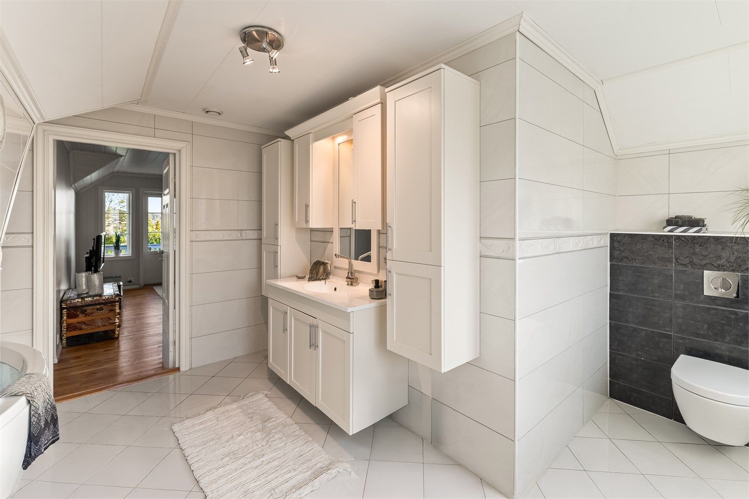 Boligens hovedbad i 2. etasje er stort og romslig, med fliser på gulv og vegger. Det er varmekabler i gulv. 