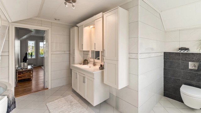 Boligens hovedbad i 2. etasje er stort og romslig, med fliser på gulv og vegger. Det er varmekabler i gulv.