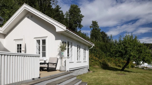 Eiendommen har en stor hage og grenser mot skogsområder i bakkant.