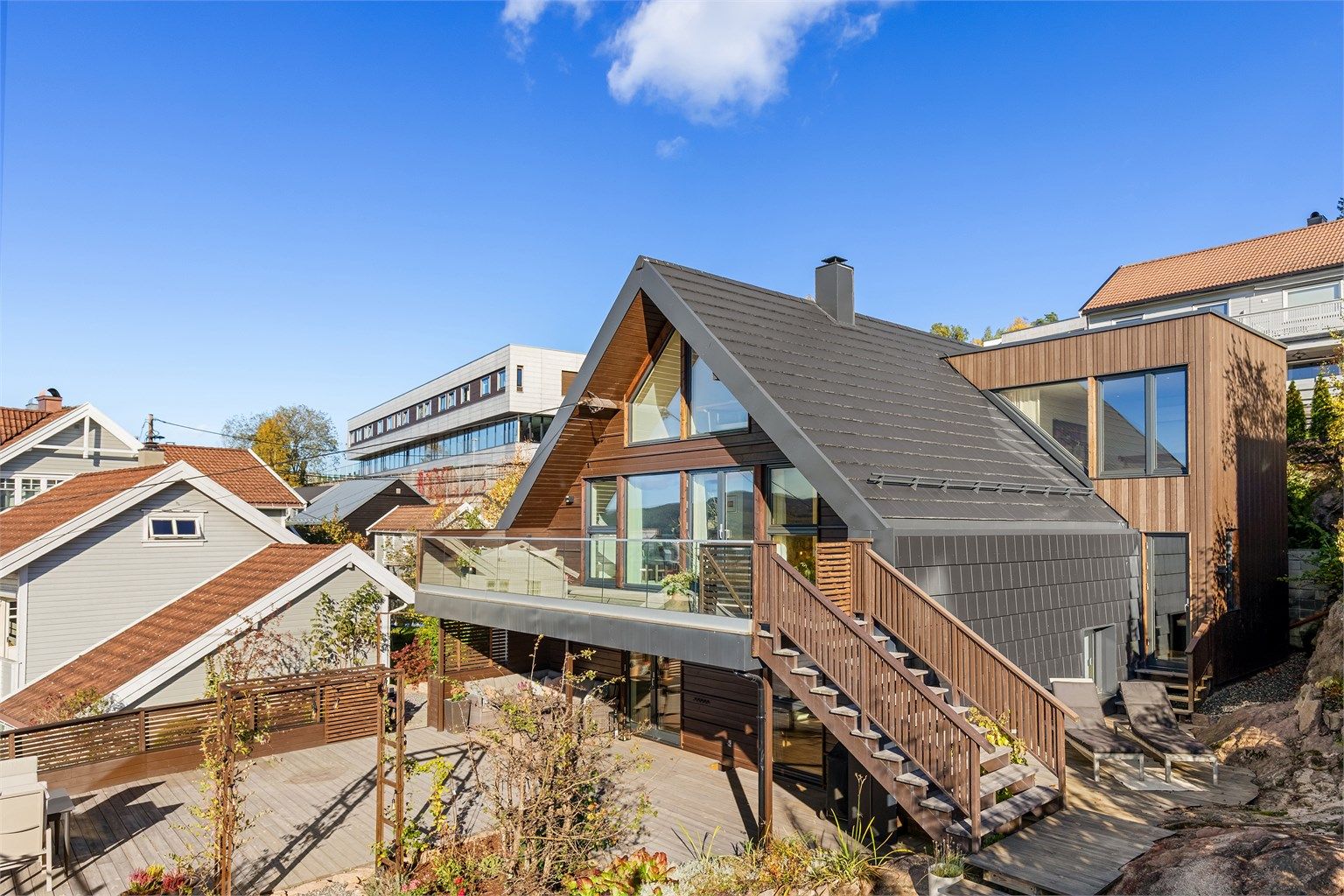 Arkitekttegnet enebolig over tre plan med påbygg og omfattende oppgraderinger fra 2021. Moderne fasader med stående og liggende trekledning samt takstein og utvendig trappeløp som forbinder uteplassene praktisk sammen. Foto: Petter Tanum/ Tanumfoto