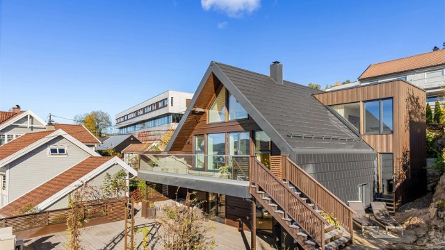 Arkitekttegnet enebolig over tre plan med påbygg og omfattende oppgraderinger fra 2021. Moderne fasader med stående og liggende trekledning samt takstein og utvendig trappeløp som forbinder uteplassene praktisk sammen. Foto: Petter Tanum/ Tanumfoto