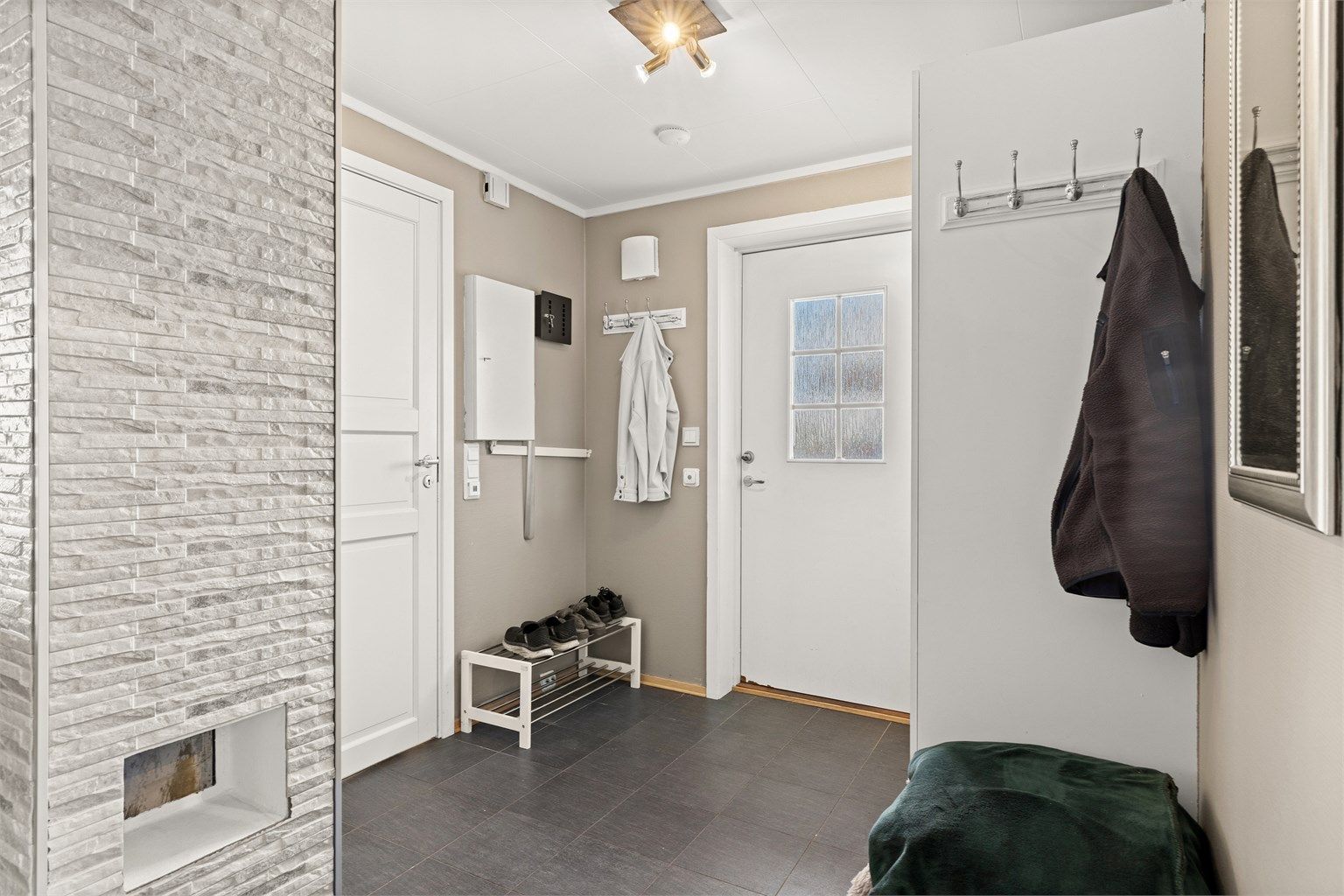 Velkommen inn i en praktisk entré med flislagt gulv og elektrisk gulvvarme.