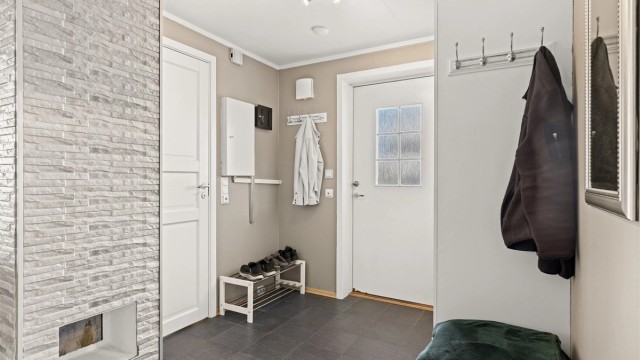 Velkommen inn i en praktisk entré med flislagt gulv og elektrisk gulvvarme.