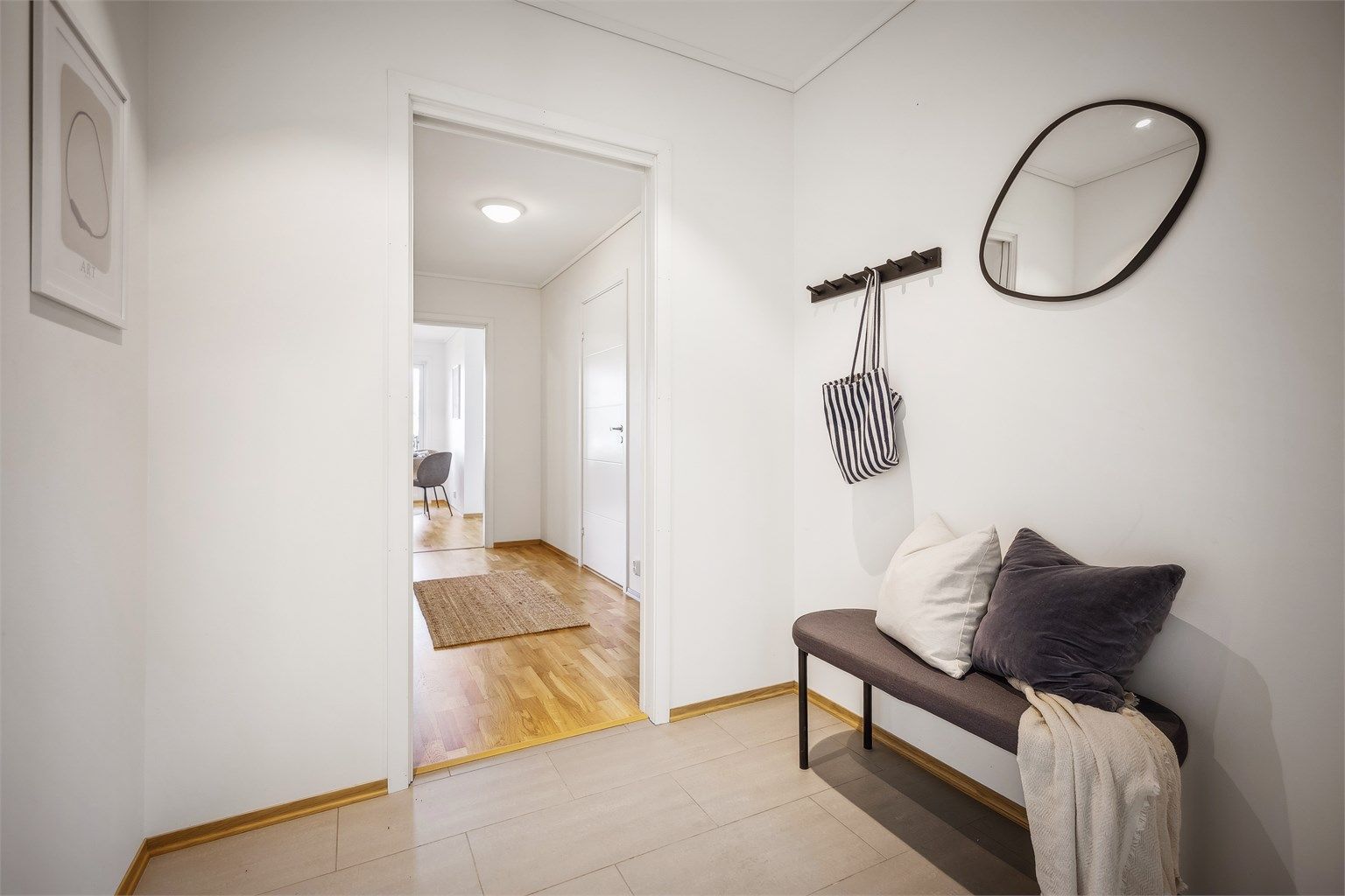 Lys og delikat entré med fliser på gulv. Her er det god plass til yttertøy og sko