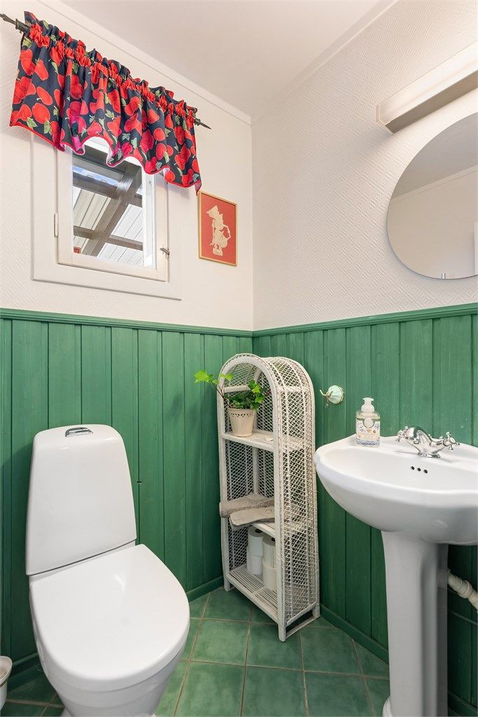 Praktisk toalettrom i første etasje med flislagt gulv og panel på veggene.