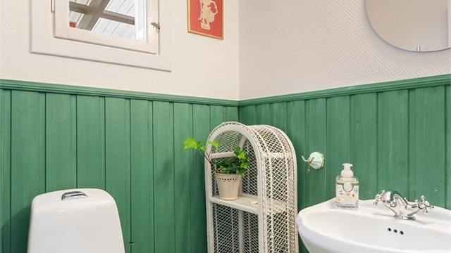 Praktisk toalettrom i første etasje med flislagt gulv og panel på veggene.