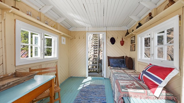 Badehuset er malt innvendig i lyse farger og har vinduer på to sider og dør direkte ut mot vannet.