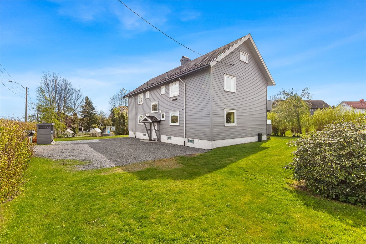 Parkering er på felles gårdsplass. Tomten er pent opparbeidet med busker, trær og blomster.