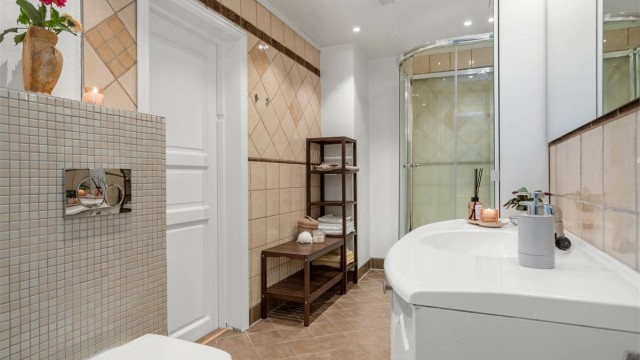 Badet er utstyrt med vegghengt toalett, servantinnredning og dusjkabinett.
