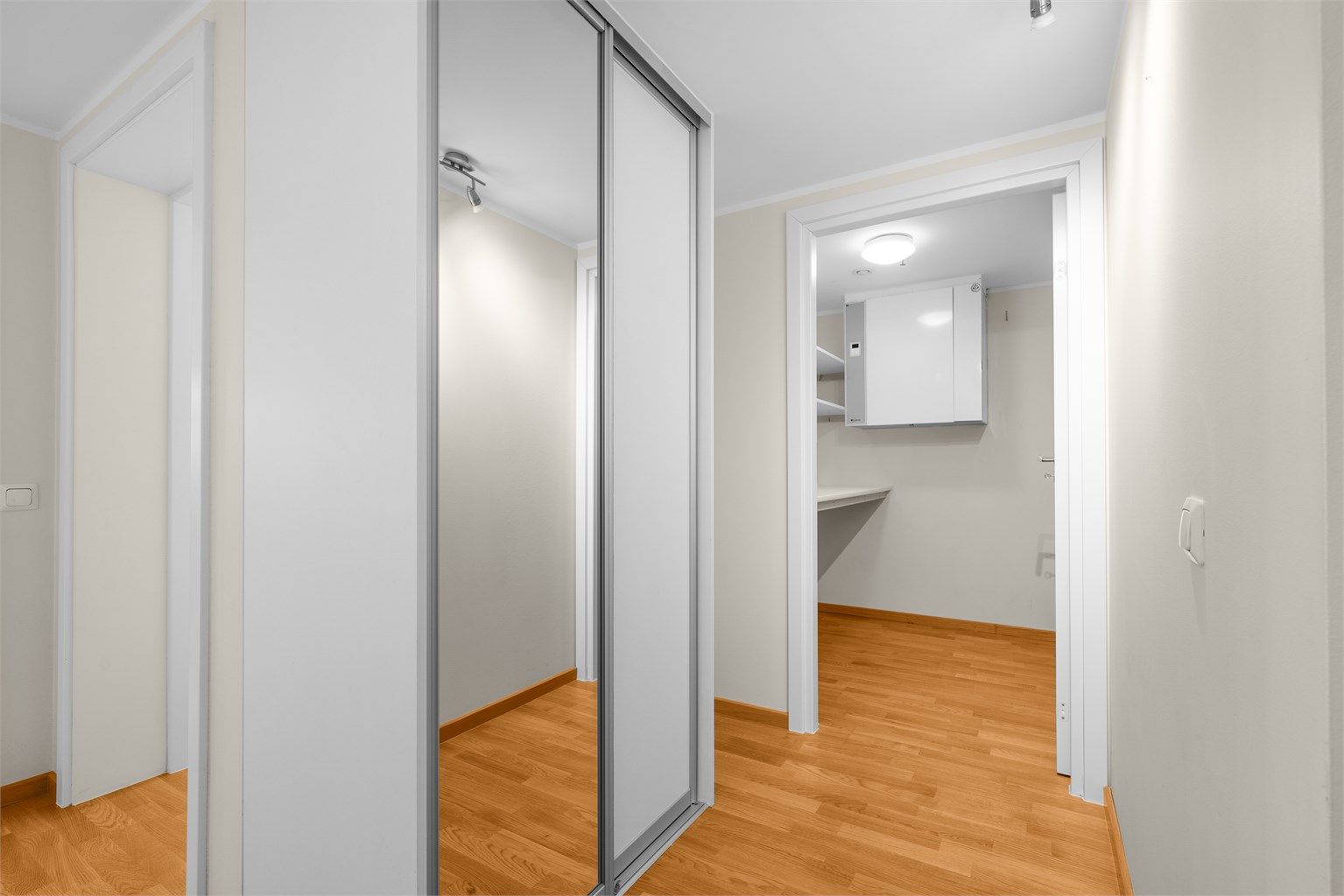 Romslig gang med praktisk skyvedørsgarderobe med speilfront
