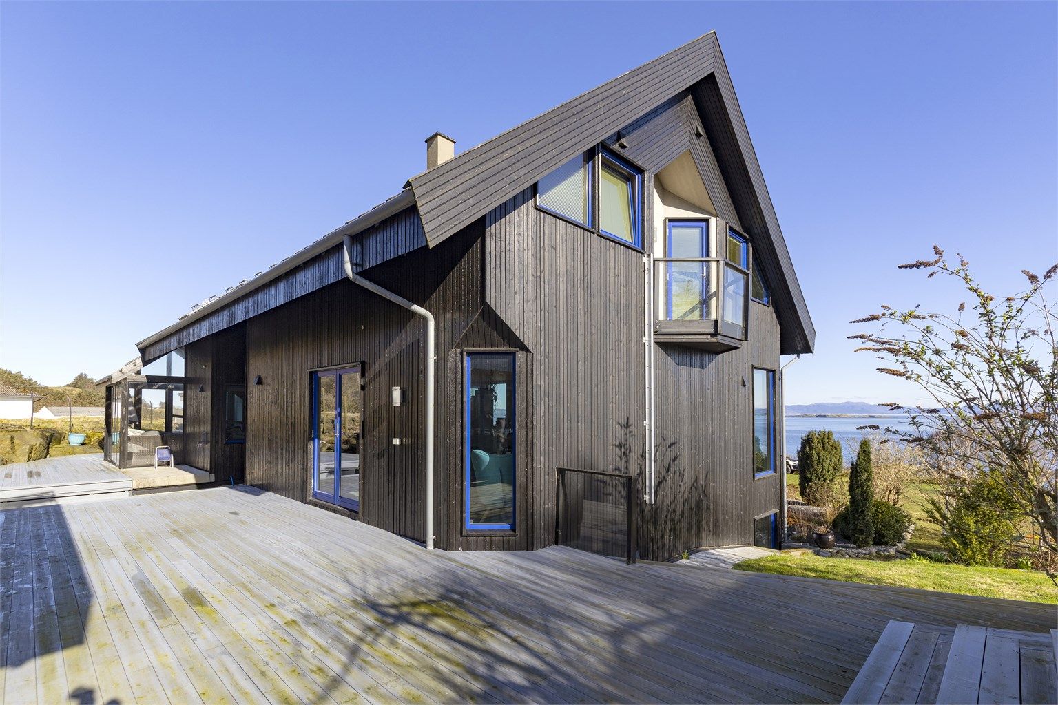 Store terrasseområder i trekonstruksjon omkranser boligen og skaper mange fine uteplasser.