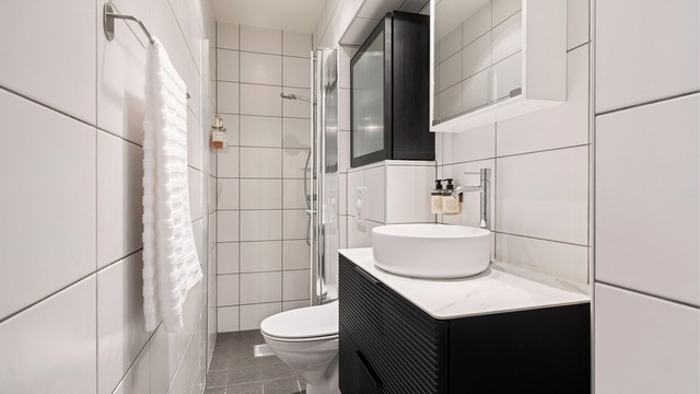 Flislagt bad med nyere innredning, servant og vegghengt toalett.