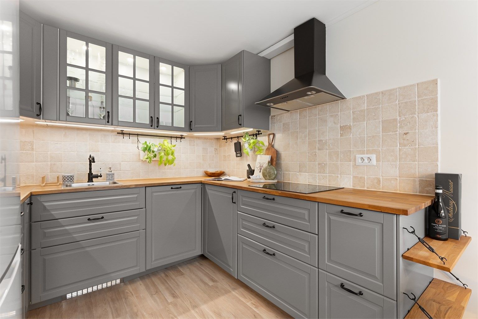 Delikat kjøkken med profilerte fronter på skap og skuffer, benkeplate av tre med kjøkkenvask og veggfliser mellom benkeplate og overskap