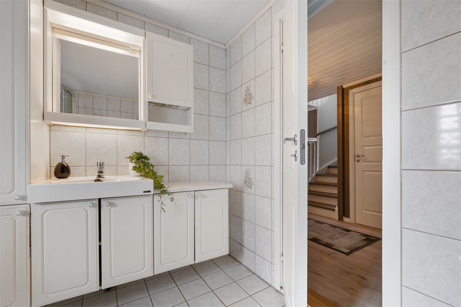 Praktisk innredning med servant og ettgreps armatur, samt høyskap og overskap med speil og belysning med tilhørende stikkontakt.