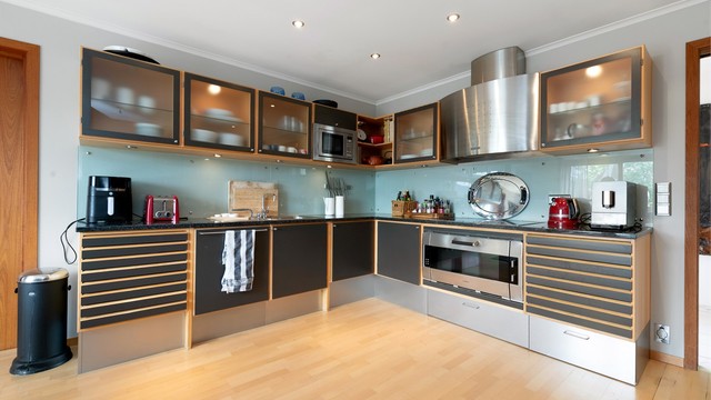 Kjøkkeninnredning fra Uno Form med benkeplate i stein og integrert stekeovn fra Gaggenau. Stål ventilator.