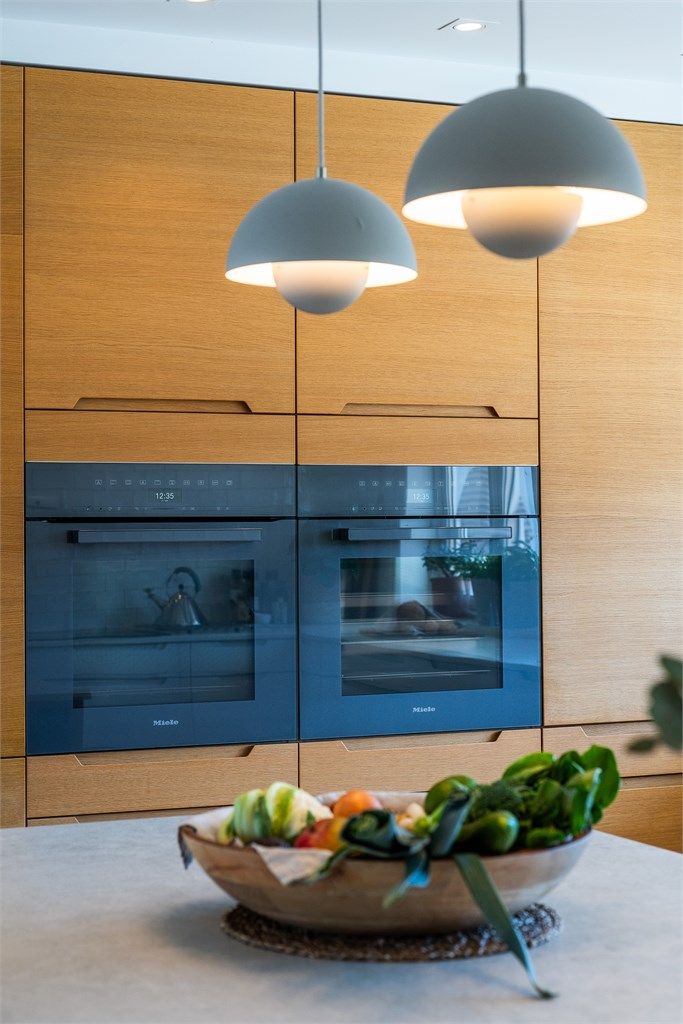 Hvitevarene er integrert i en heltre eikevegg, med blant annet komfyr og dampovn fra Miele.