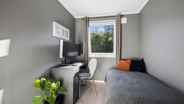 Et hyggelig og lyst soverom med fint lysinnslipp og plass til både seng og praktisk arbeidsplass.
