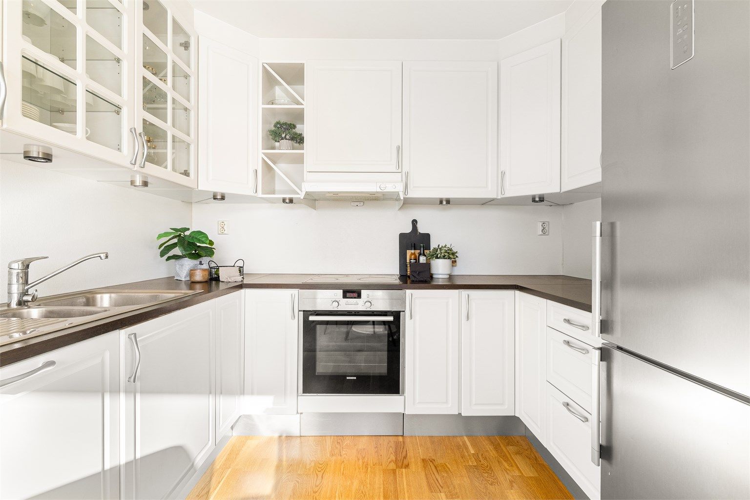 Klassisk kjøkkeninnredning med hvite profilerte fronter. Det er installert fuktsensor til automatisk vannstopper under oppvaskkum.