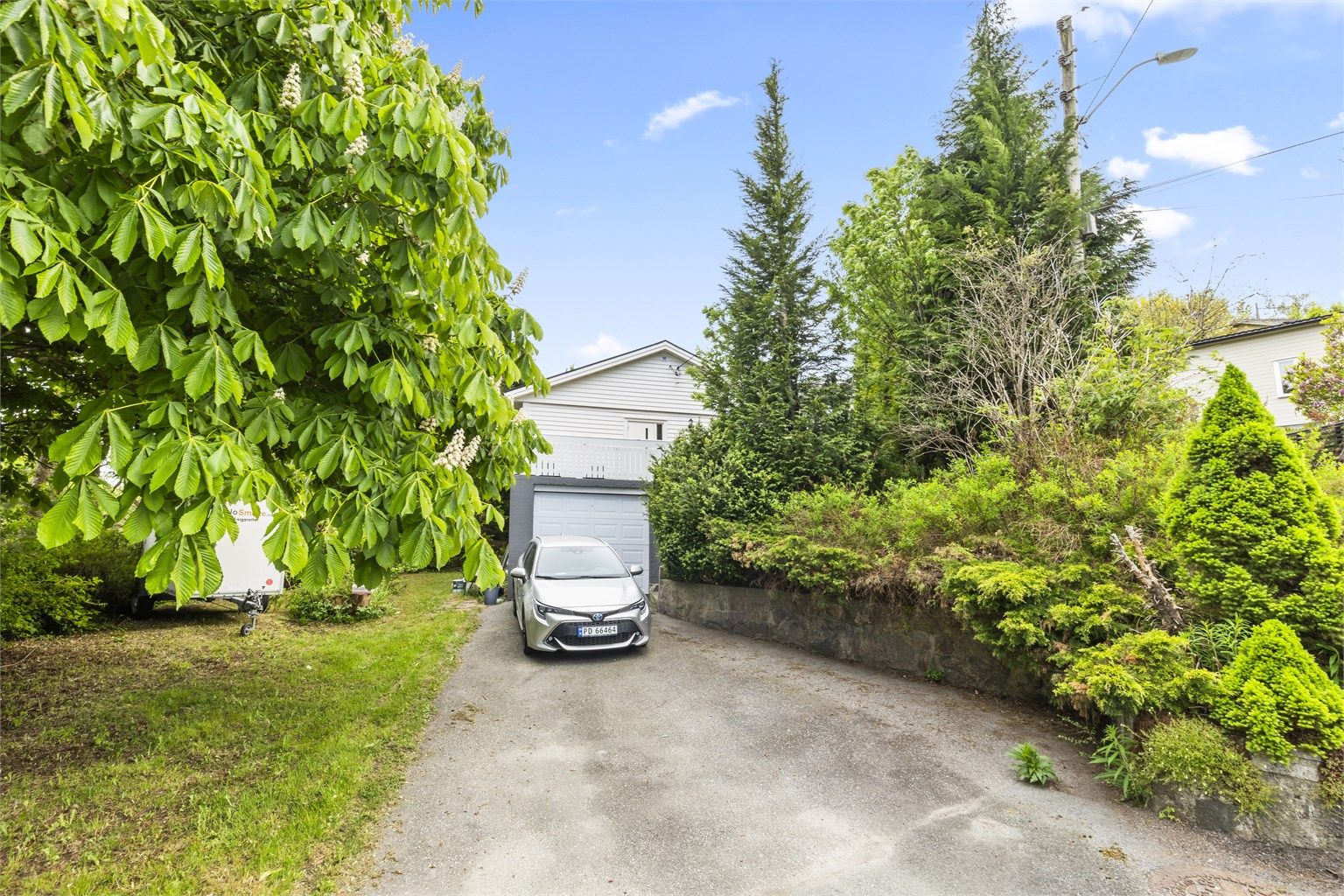 Asfaltert innkjørsel med biloppstillingsplasser og garasje