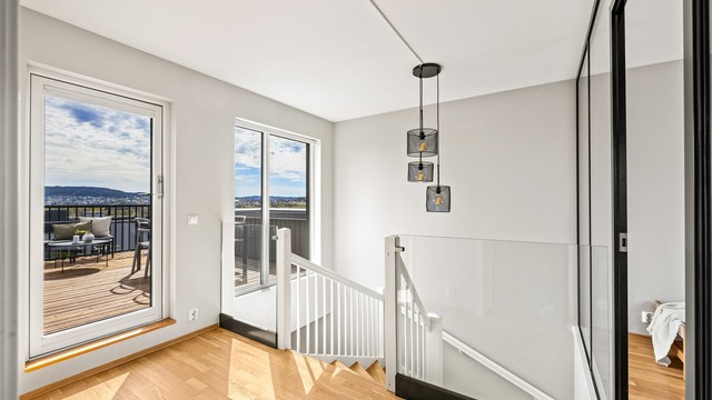 Fra gangen i andre etasje er det utgang til den sydvendte takterrassen. Rekkverk i herdet glass sikrer lysinnslipp og utsikt.
