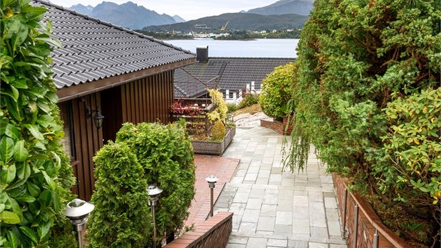 Skifertrapp med rekkverk leder fra adkomstveien ned mot inngangen.